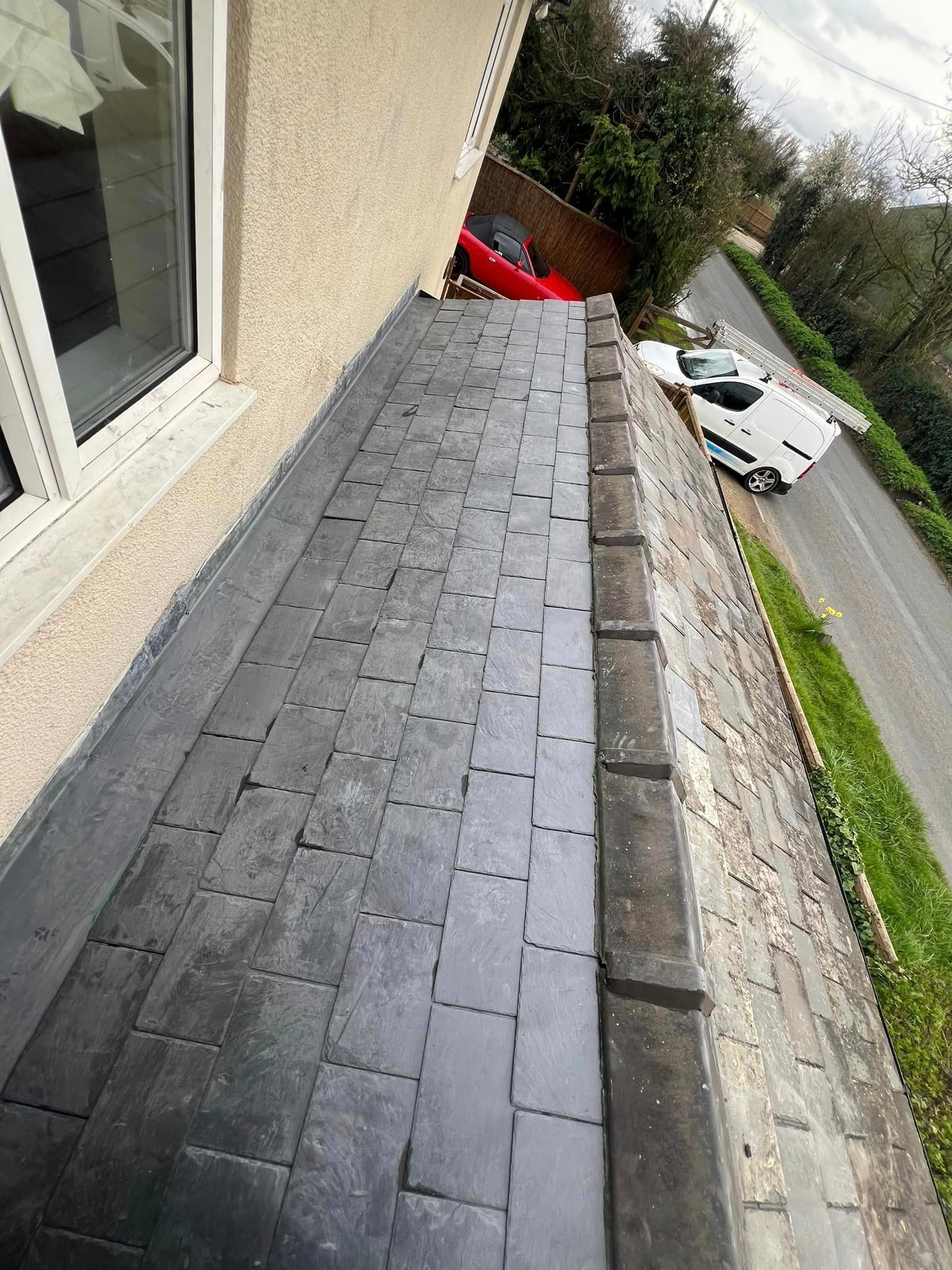 A slate roof is being installed on the side of a house.
