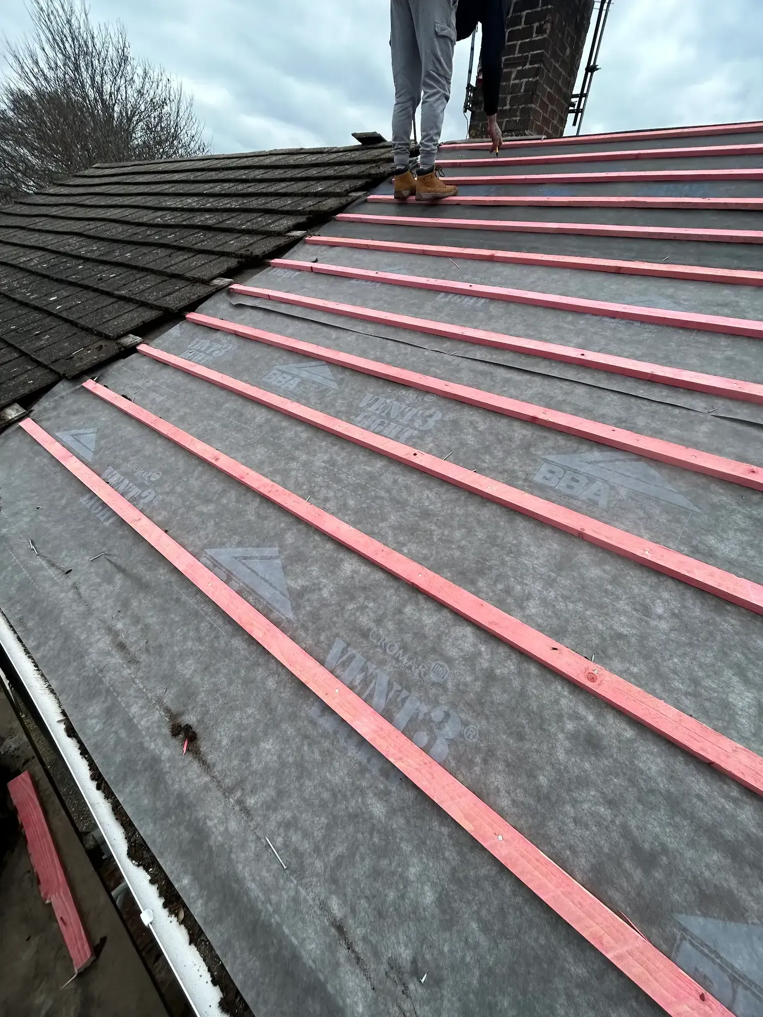 A person is standing on top of a roof with pink stripes.