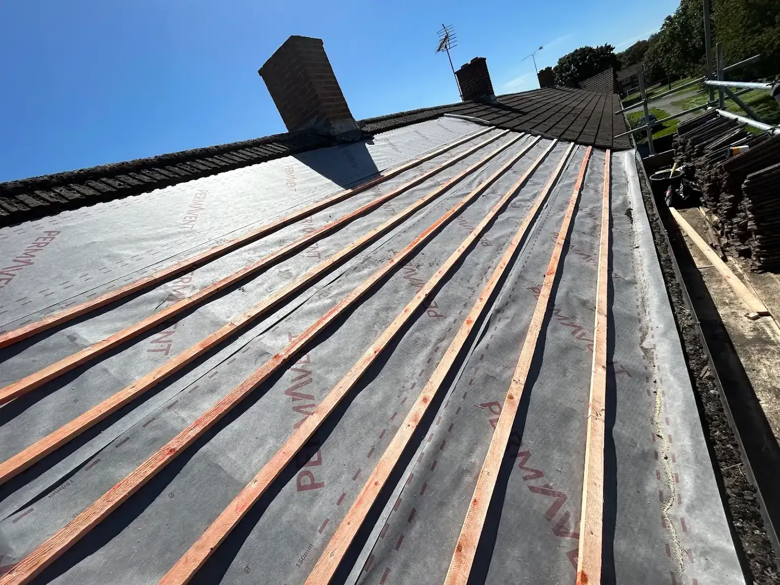 A roof that is being built with a chimney in the background