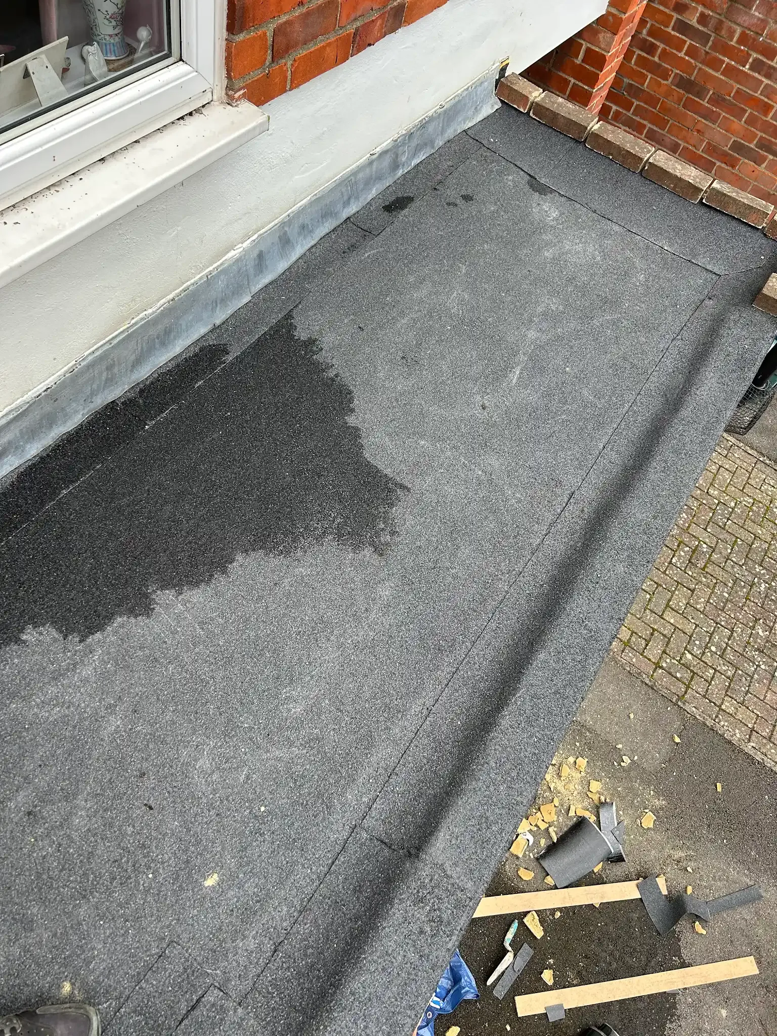 A close up of a roof with a brick wall in the background.