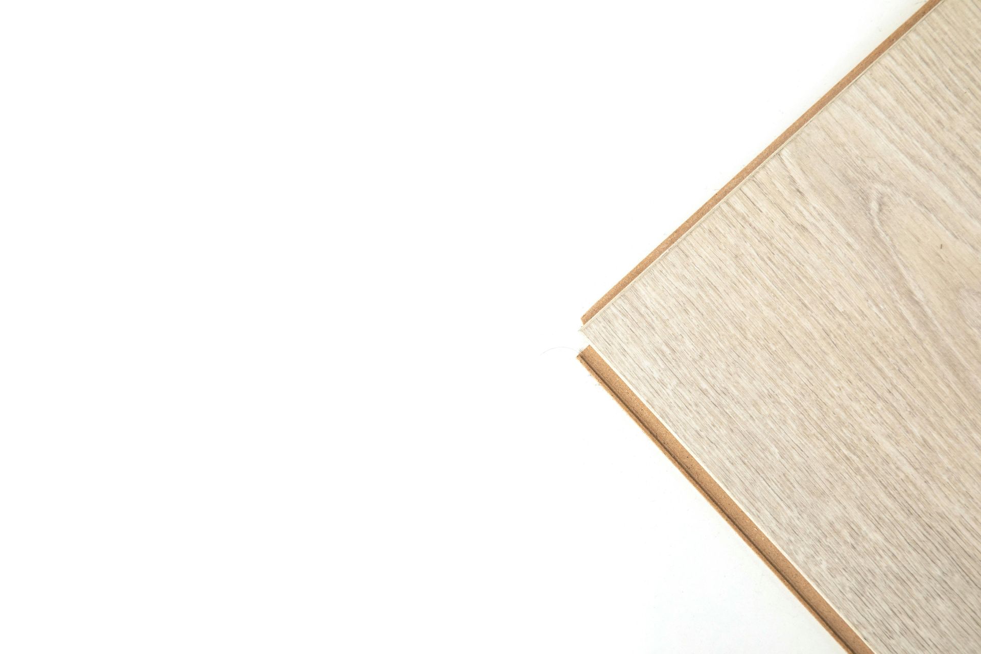 A wooden laminate flooring plank corner against a solid white background.