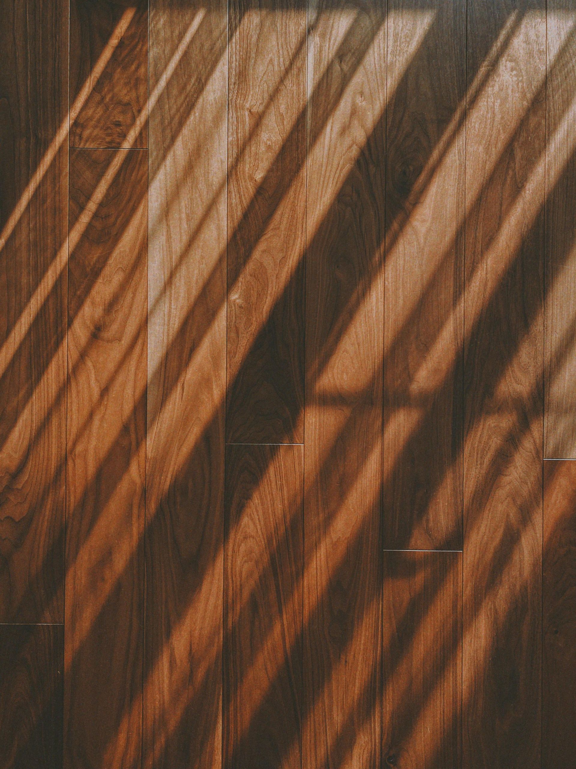 Diagonal streaks of sunlight and shadows cast across a textured wooden floor.