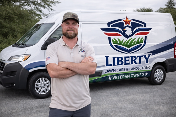 Man standing in front of a Liberty Lawn Care & Landscaping van, arms crossed, smiling.