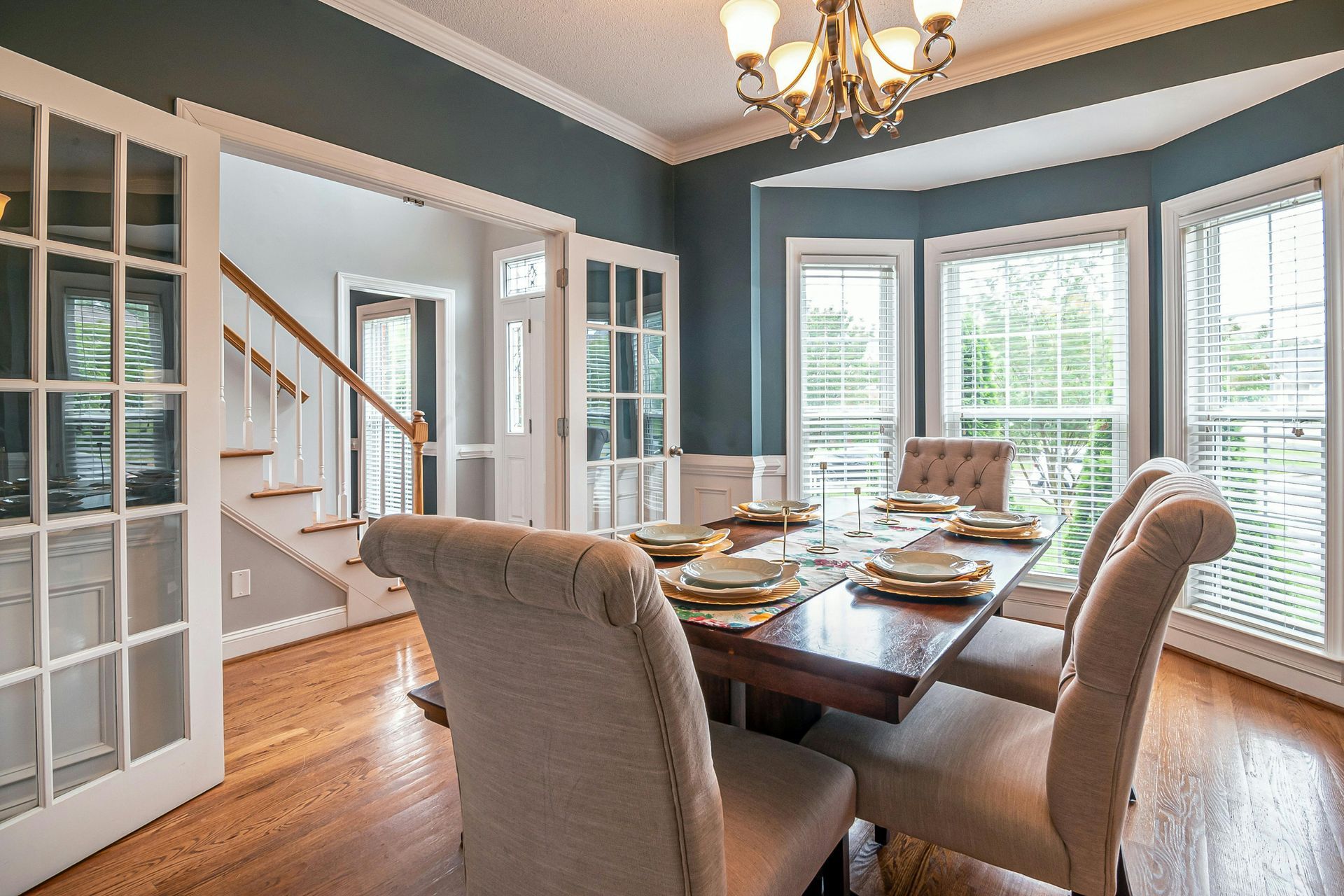 Dining room with a set table, chandelier, bay windows, and glass-paneled double doors