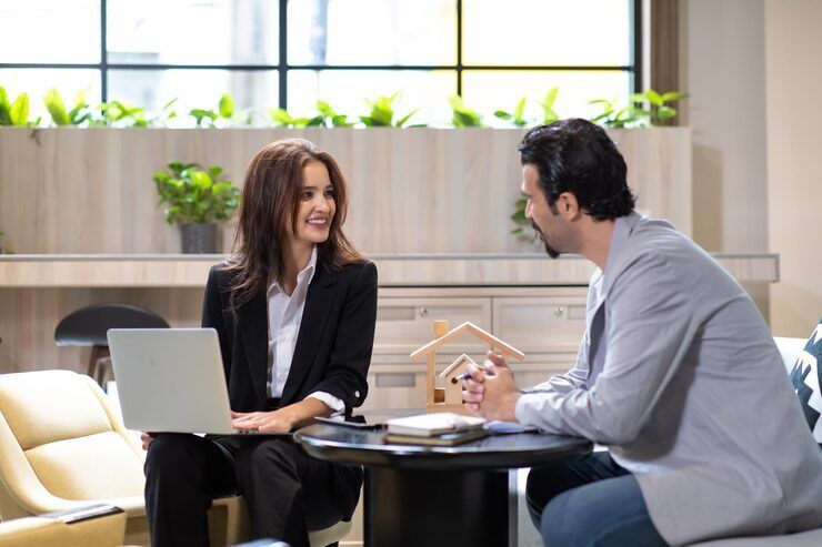 Two people talking over coffee in a bright office lounge, one using a laptop