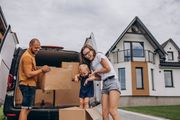 Family loading moving boxes into a car outside a suburban house