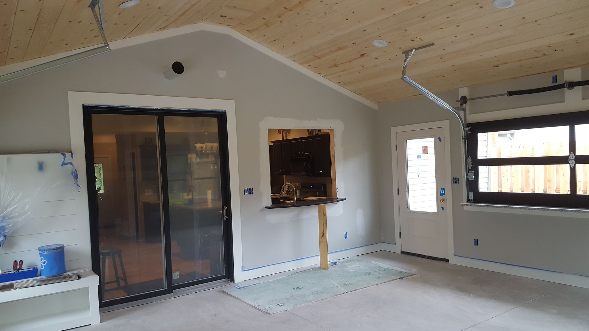 Empty room with beige walls, sliding glass doors, and a large window under a sloped ceiling.
