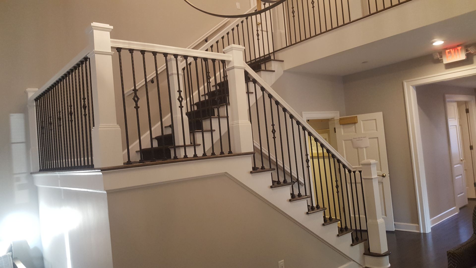 Interior staircase with white railings and beige walls in a hallway lobby.