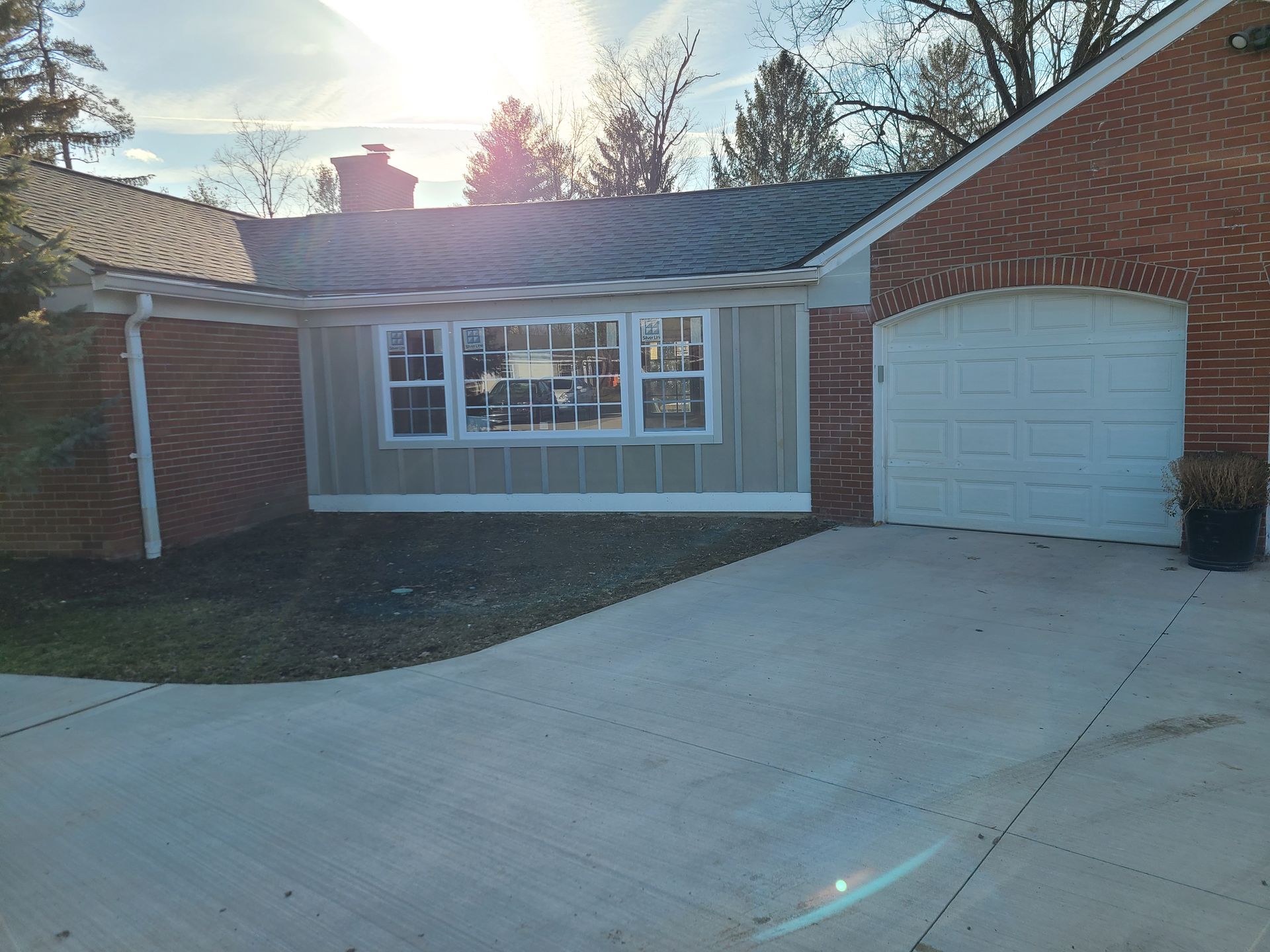 Suburban brick house with a white garage door and concrete driveway in bright sunlight