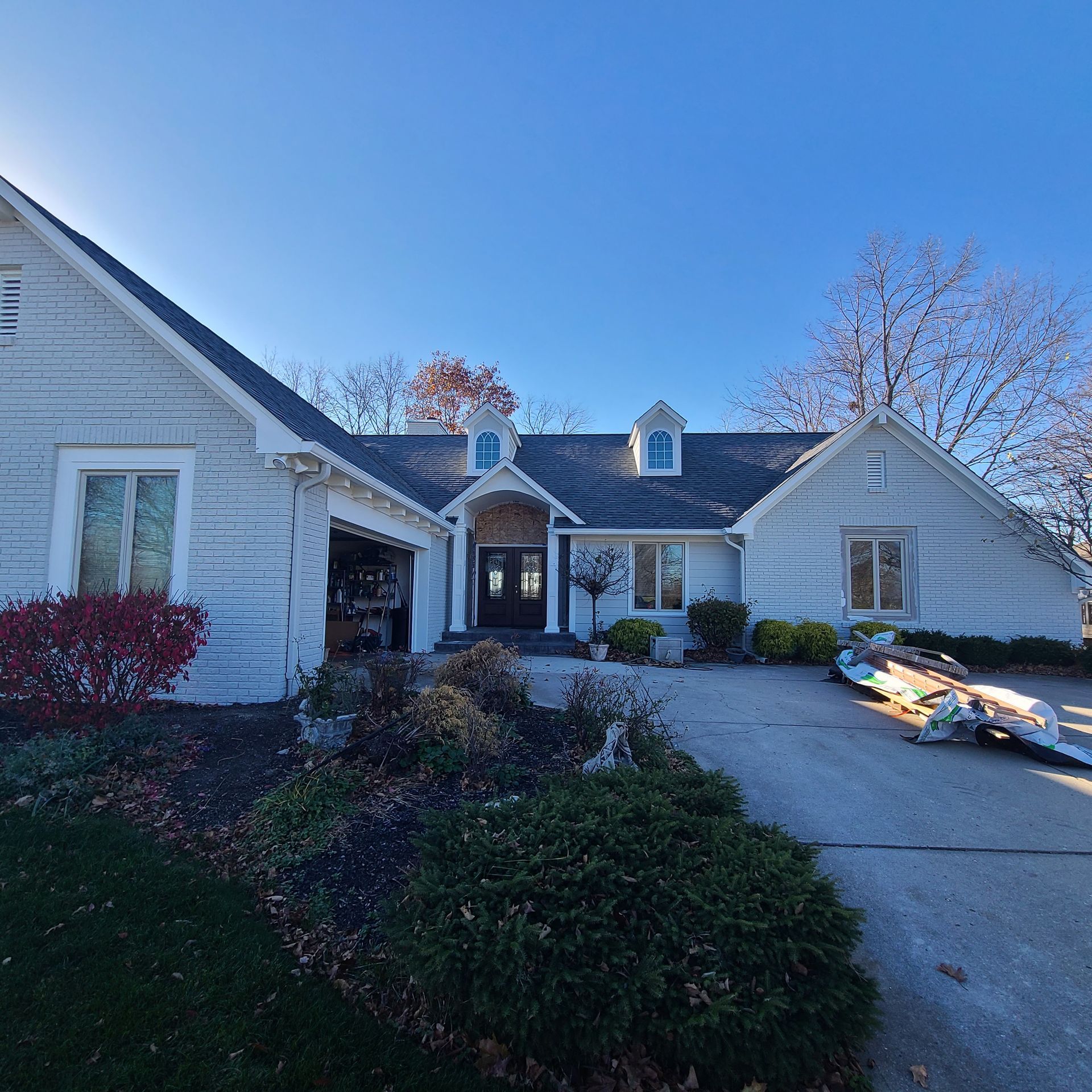 White house with a gabled roof, front walkway, and winter landscaping under a clear blue sky