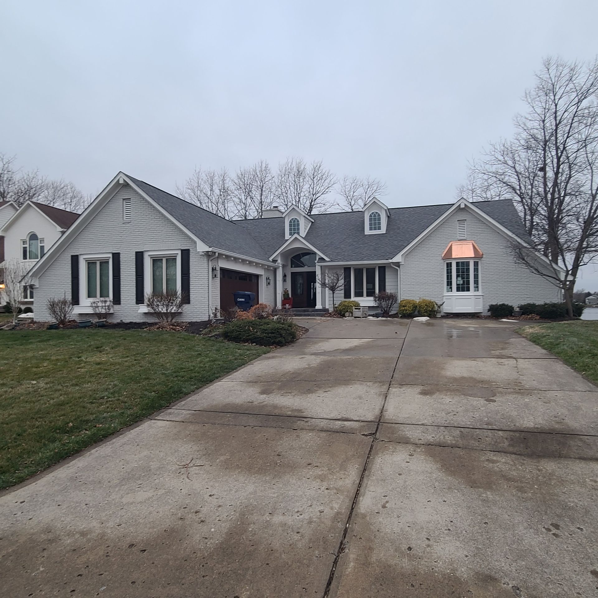 Suburban house with a wide concrete driveway on an overcast day
