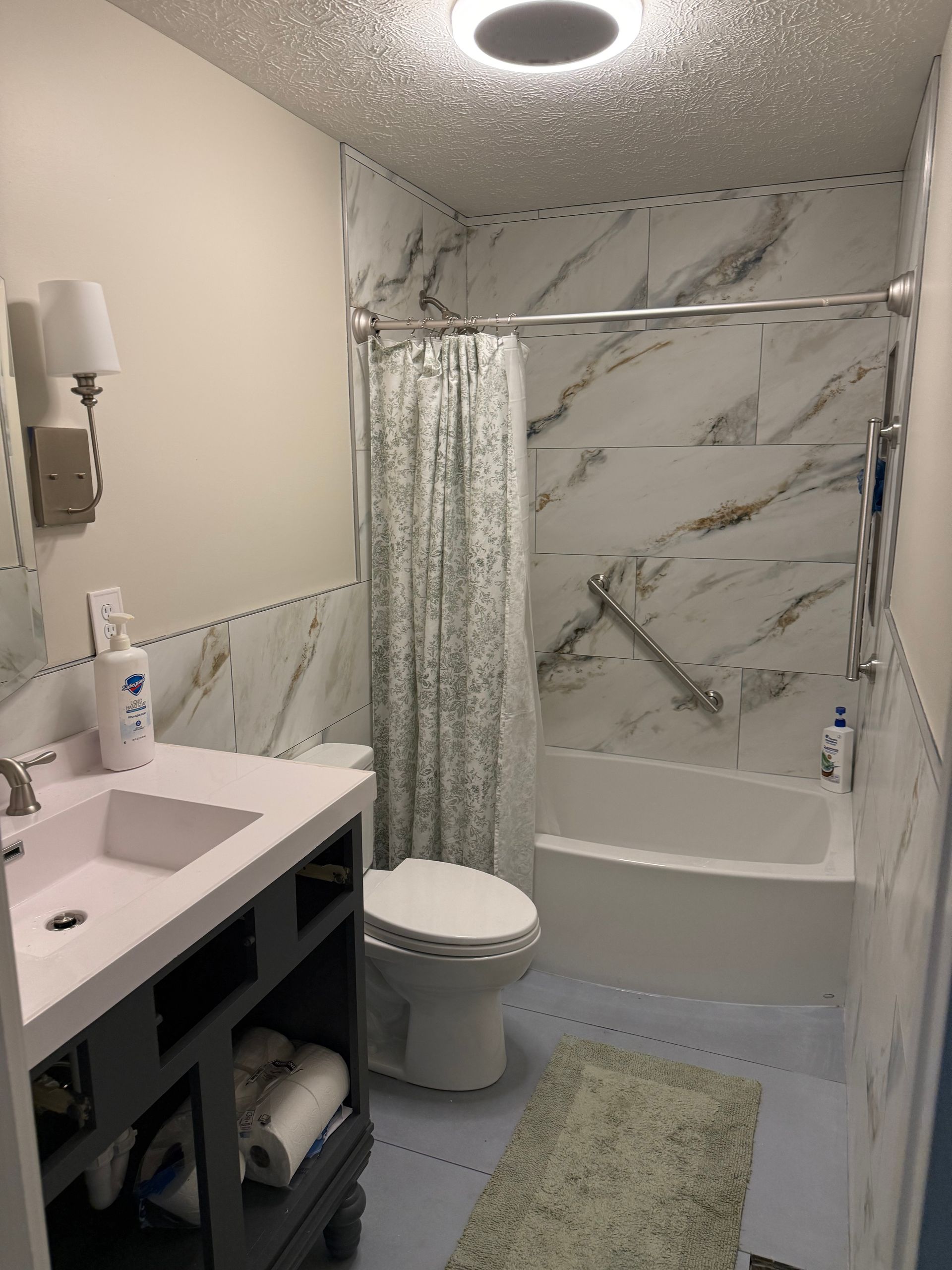 Small modern bathroom with marble shower, sink vanity, toilet, and ceiling light