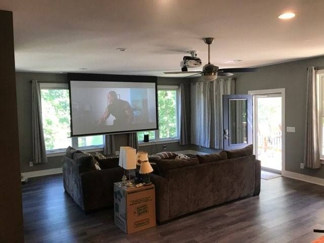 Cozy living room with projector screen, sectional sofa, and large windows, set up for home movie night