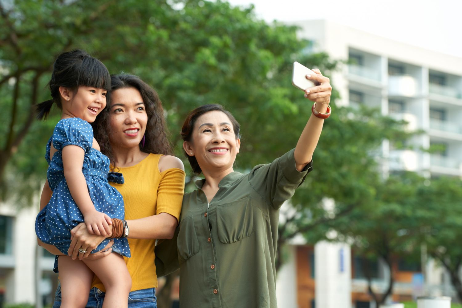 A woman is taking a selfie with her family in a park.