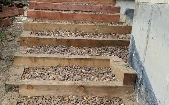 A set of wooden stairs made of wood and gravel next to a building.