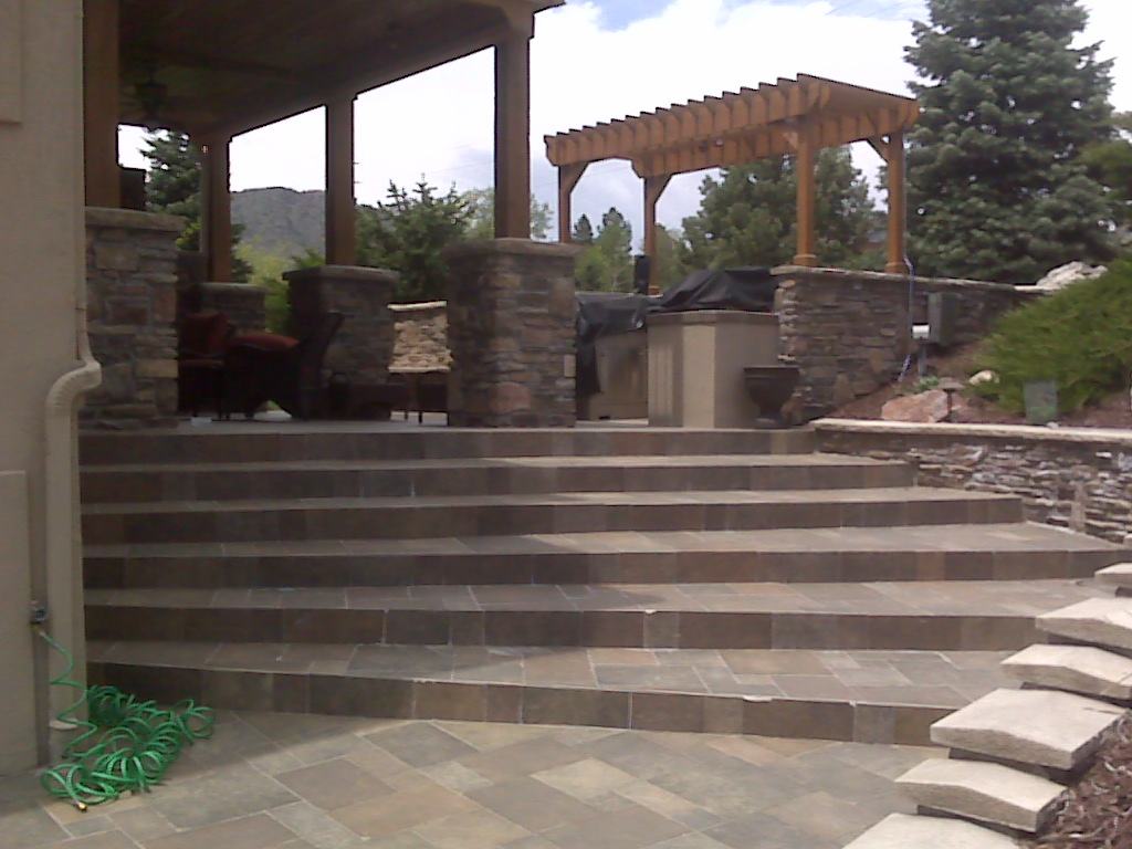 A stone patio with stairs leading up to a pergola