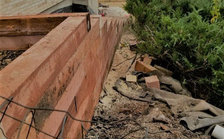 A brick wall is being built next to a house.