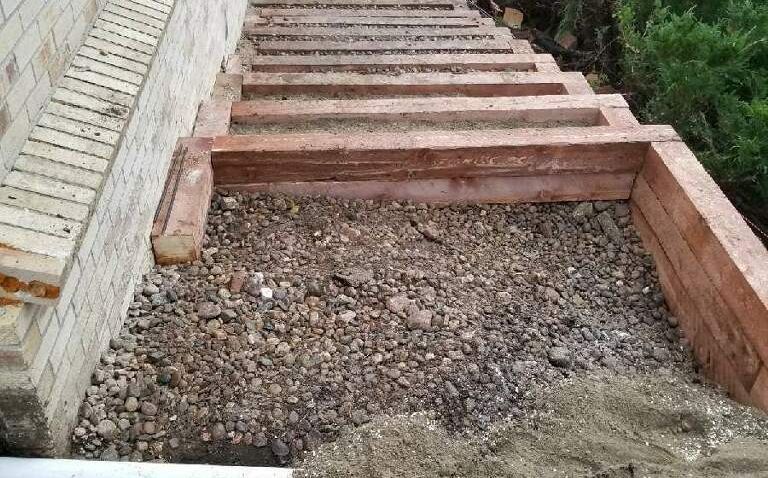 A wooden staircase is being built next to a brick wall.