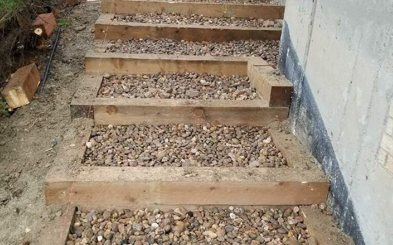 A set of wooden stairs made of wooden beams and gravel.