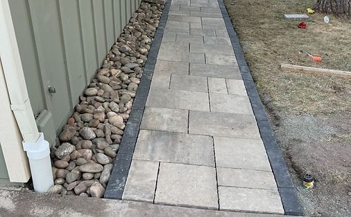 A stone walkway leading to a house with rocks on the side.
