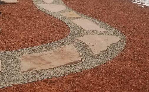A walkway made of gravel and rocks going through a pile of mulch