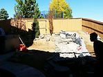 A man is sitting in a chair in a backyard.