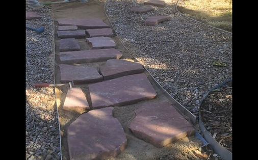 A stone walkway is being built on a gravel road