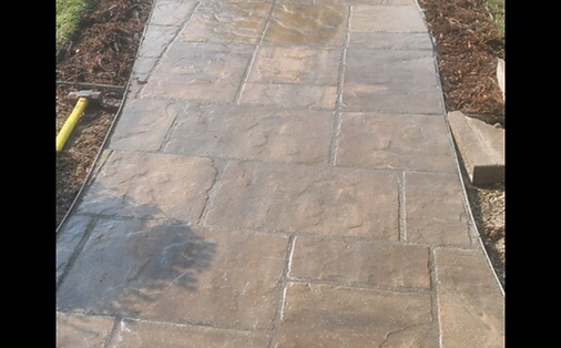 A concrete walkway with a yellow hammer on the side of it.