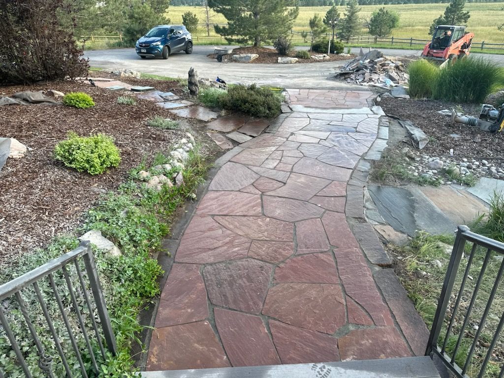 A car is parked on the side of the road next to a stone walkway.