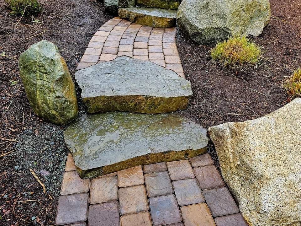 Stone pathway with large stepping stones and surrounding rocks.