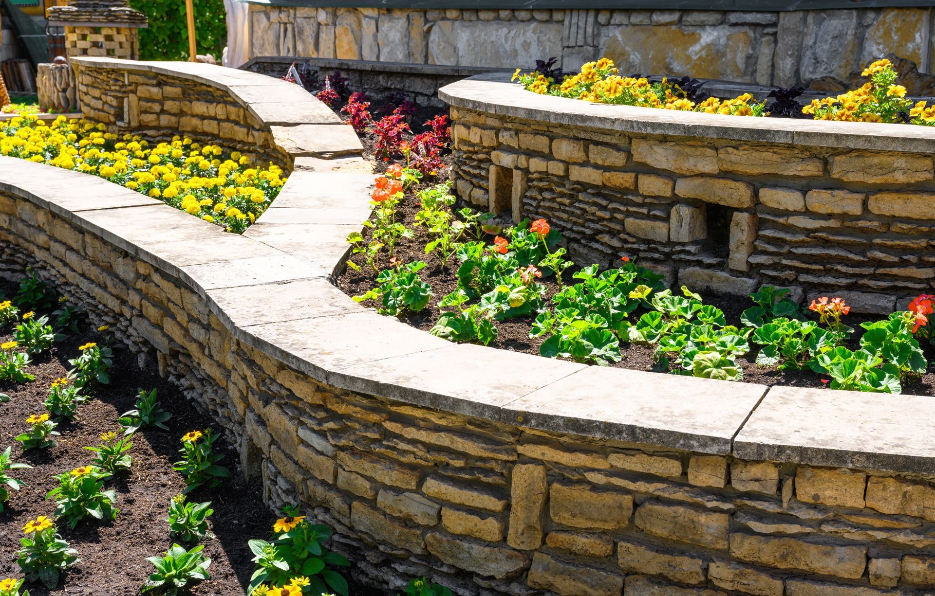 A stone wall surrounded by flowers in a garden.