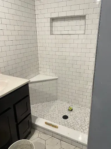 Marble-tiled shower with a black showerhead and curtain rod.