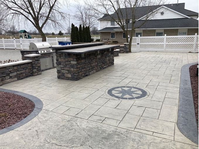 Outdoor patio with stone bar, grill, and stamped concrete.