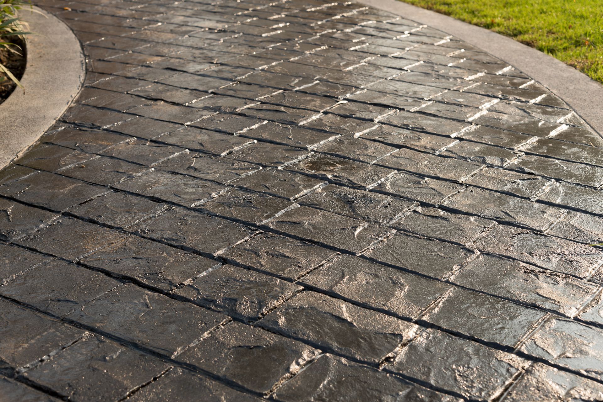Beautiful stamped concrete walkway leading to a house, enhanced by vibrant landscaping.