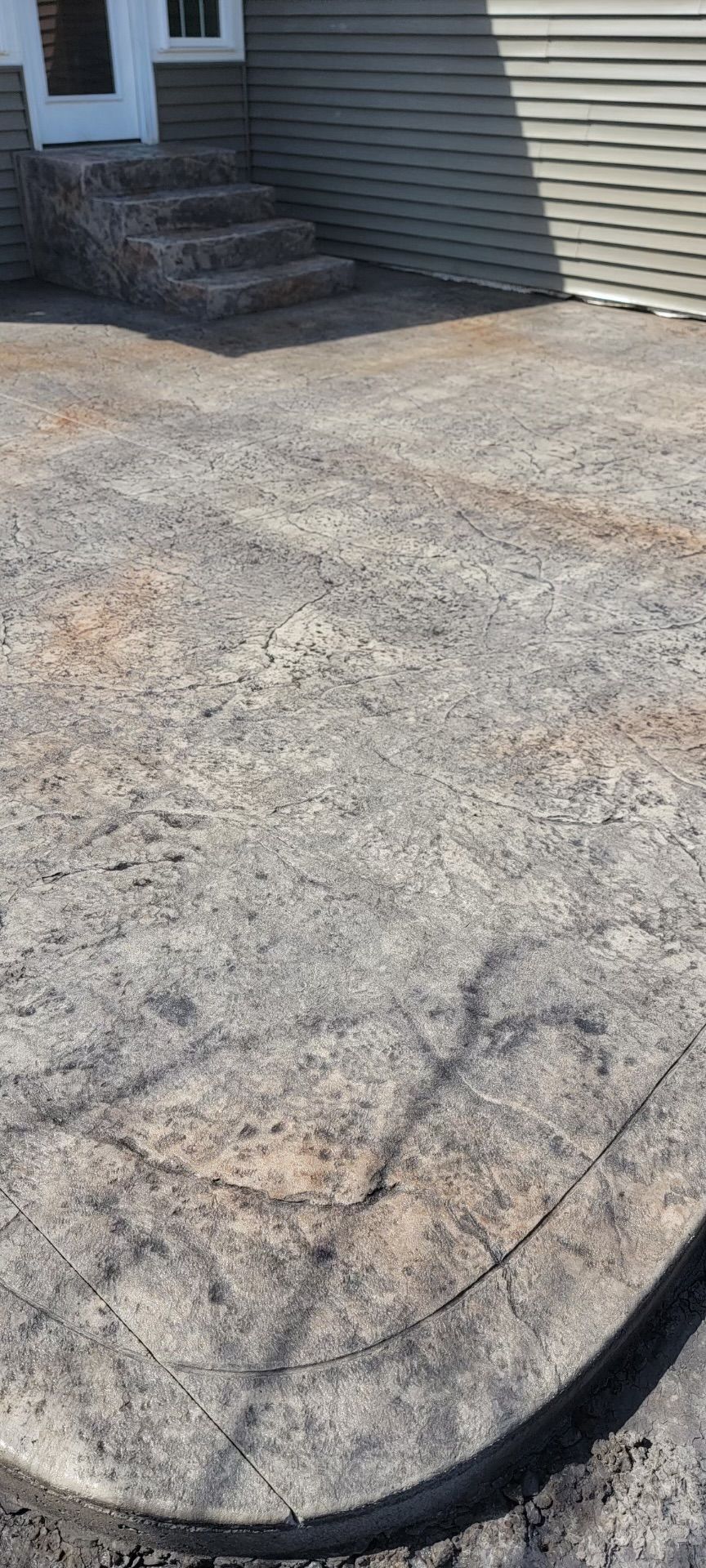 Gravel driveway leading to steps of a house. Black edging along the bottom.