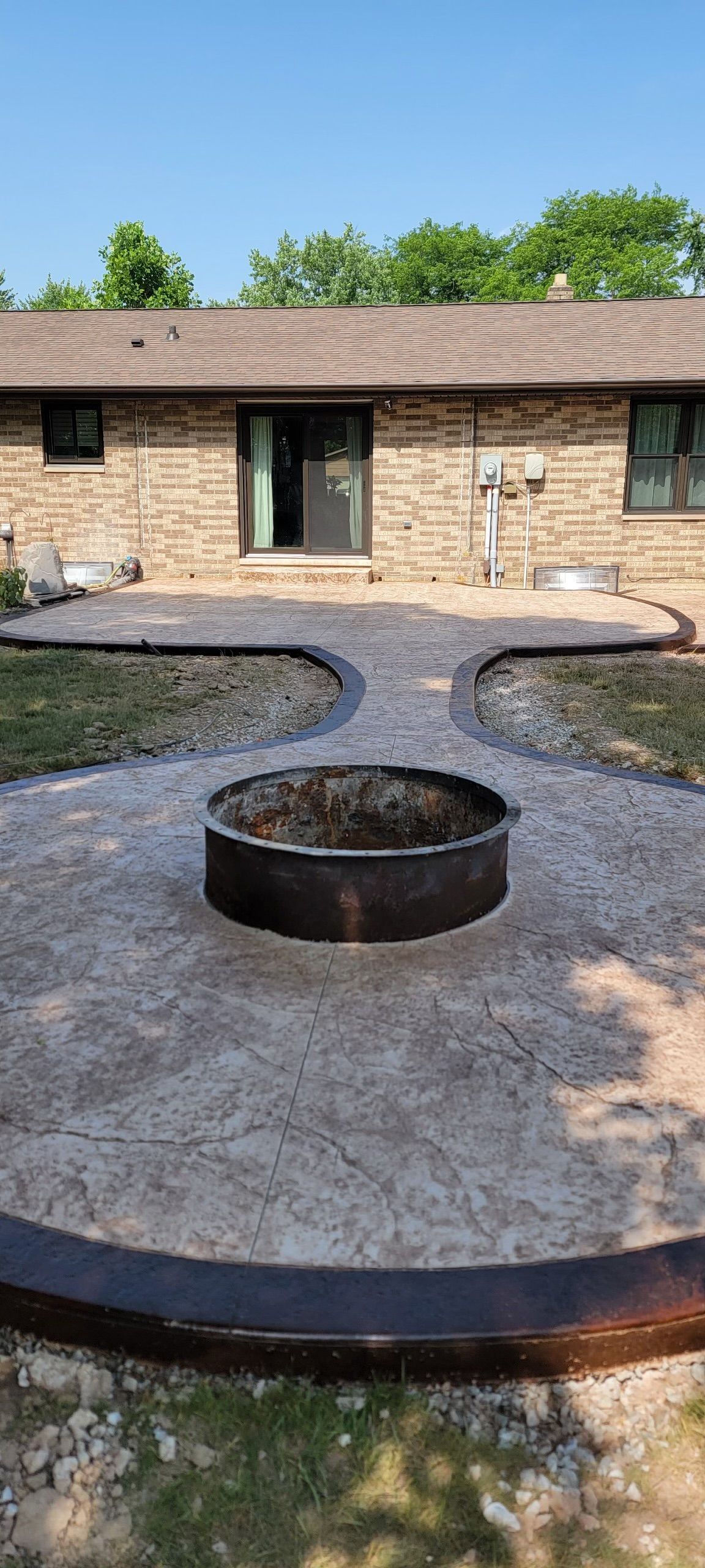 A used fire pit is in the middle of a concrete patio