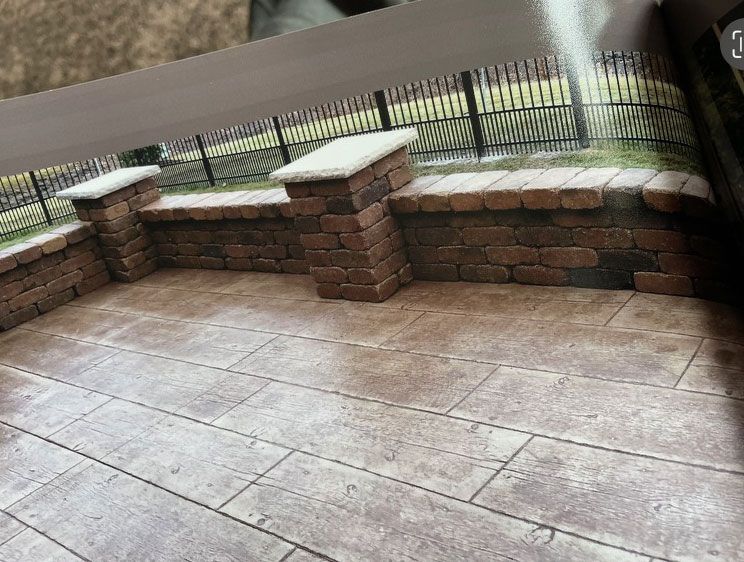 Brick patio with low wall and pillars, topped with white caps, and black fence in the background.