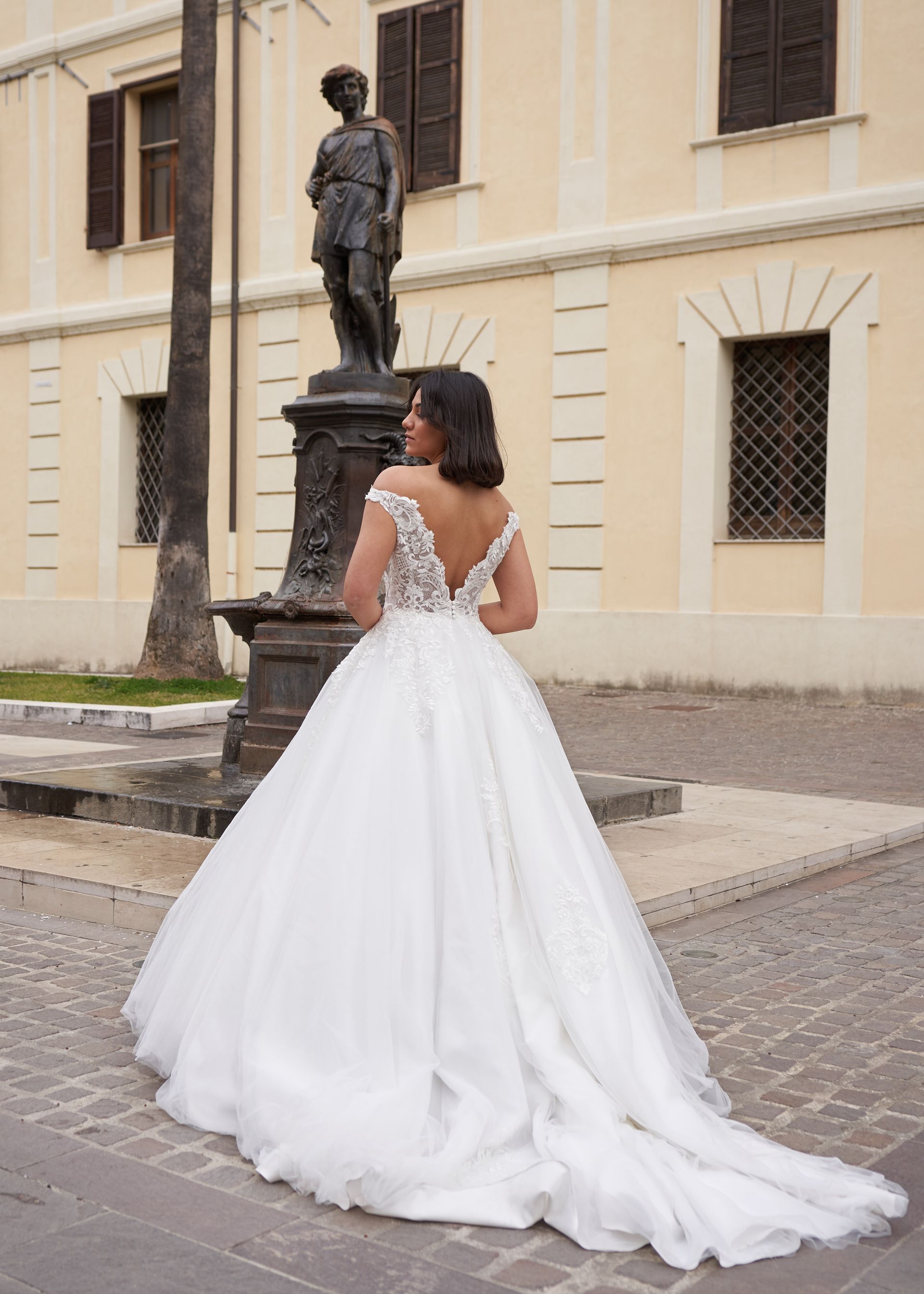 Una donna in abito da sposa è in piedi davanti a un edificio.