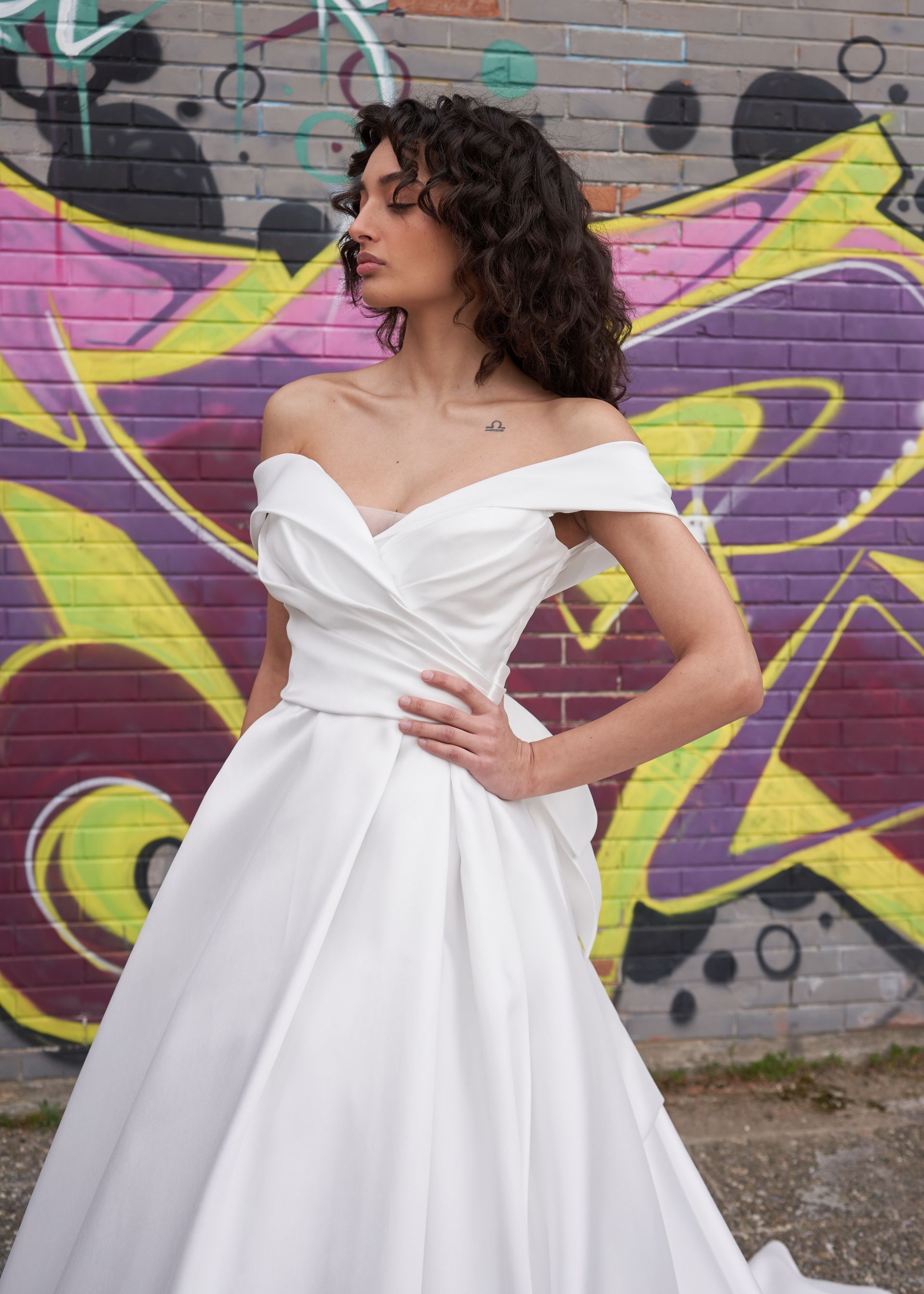 Una donna vestita di bianco è in piedi davanti a un muro di graffiti.