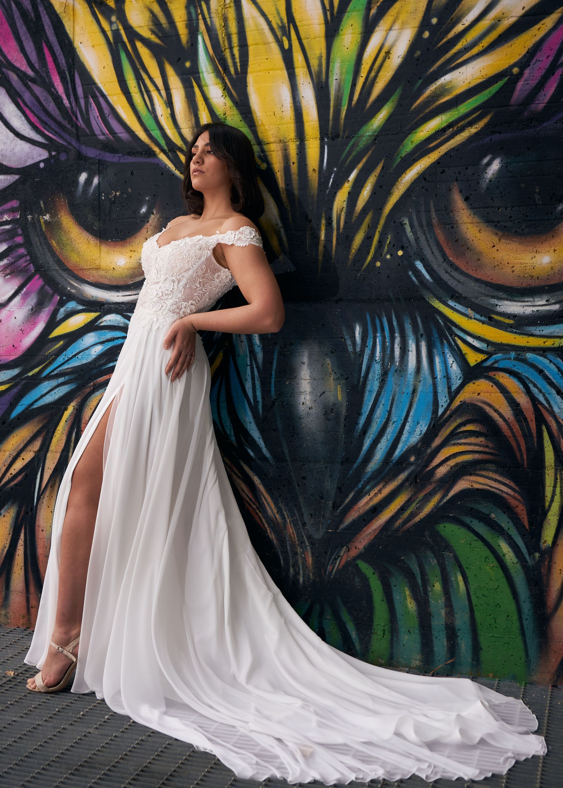 Una donna in abito da sposa è in piedi davanti a un muro di graffiti.