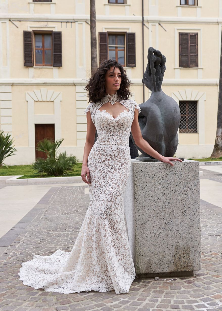 Una donna in abito da sposa è in piedi accanto a una statua.