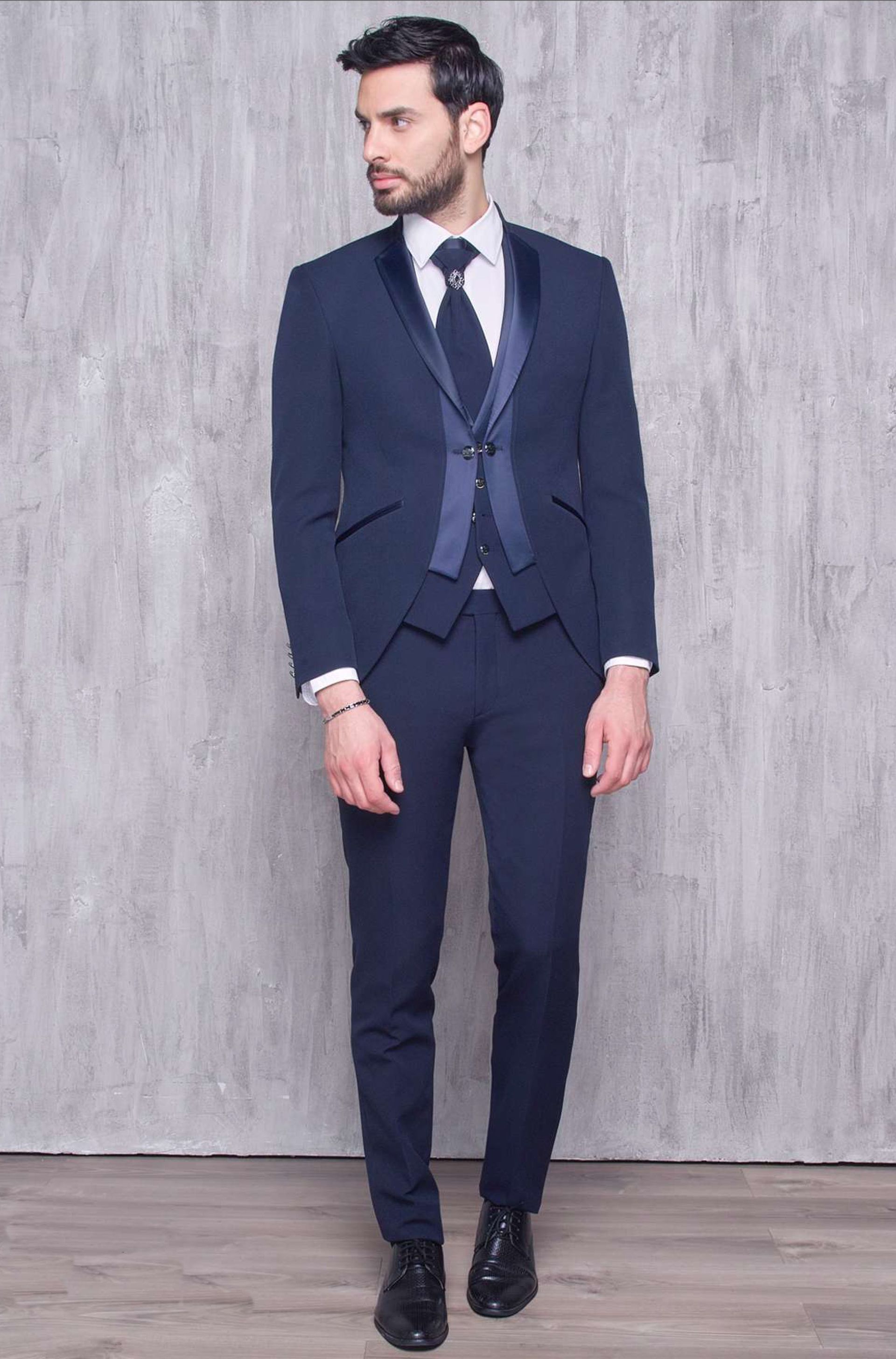 Un uomo in abito blu e cravatta è in piedi davanti a un muro.