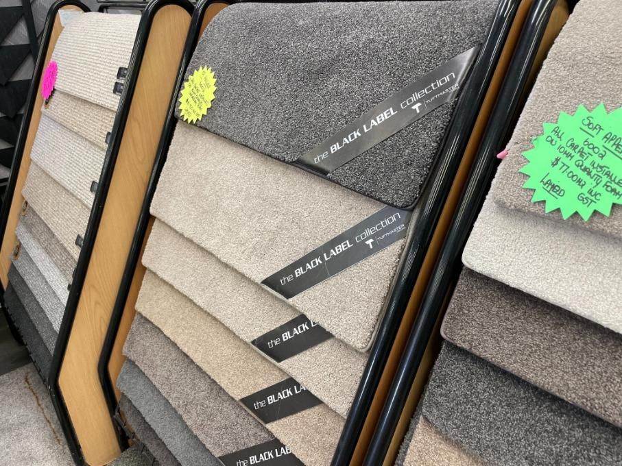 A Display of Carpets in a Store With a Green Sign — Traditional Tiles & Flooring in Gordonvale, QLD