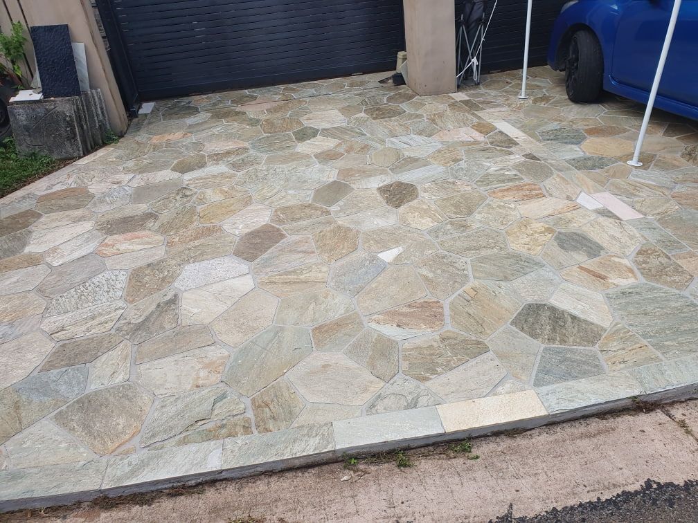 A Blue Car Is Parked in A Driveway Next to A Garage — Traditional Tiles & Flooring In Woree, QLD