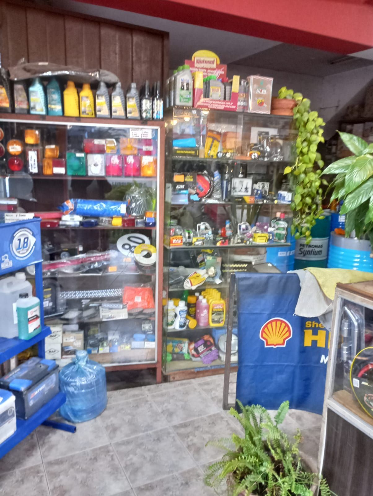 Interior de una pequeña tienda con estantes llenos de aperitivos, bebidas y artículos para el hogar.