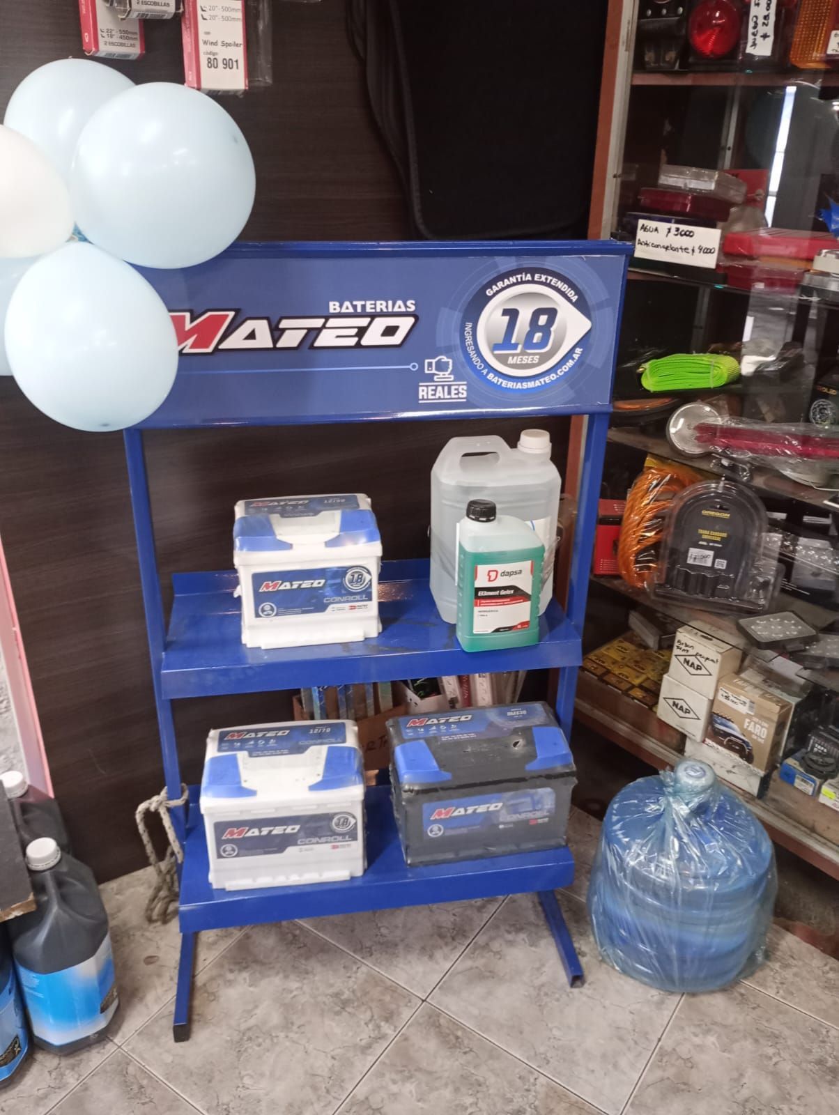 Estantería expositora de Blue Vageo con fluidos para automóviles, neumáticos y globos azul claro en un pasillo de la tienda.