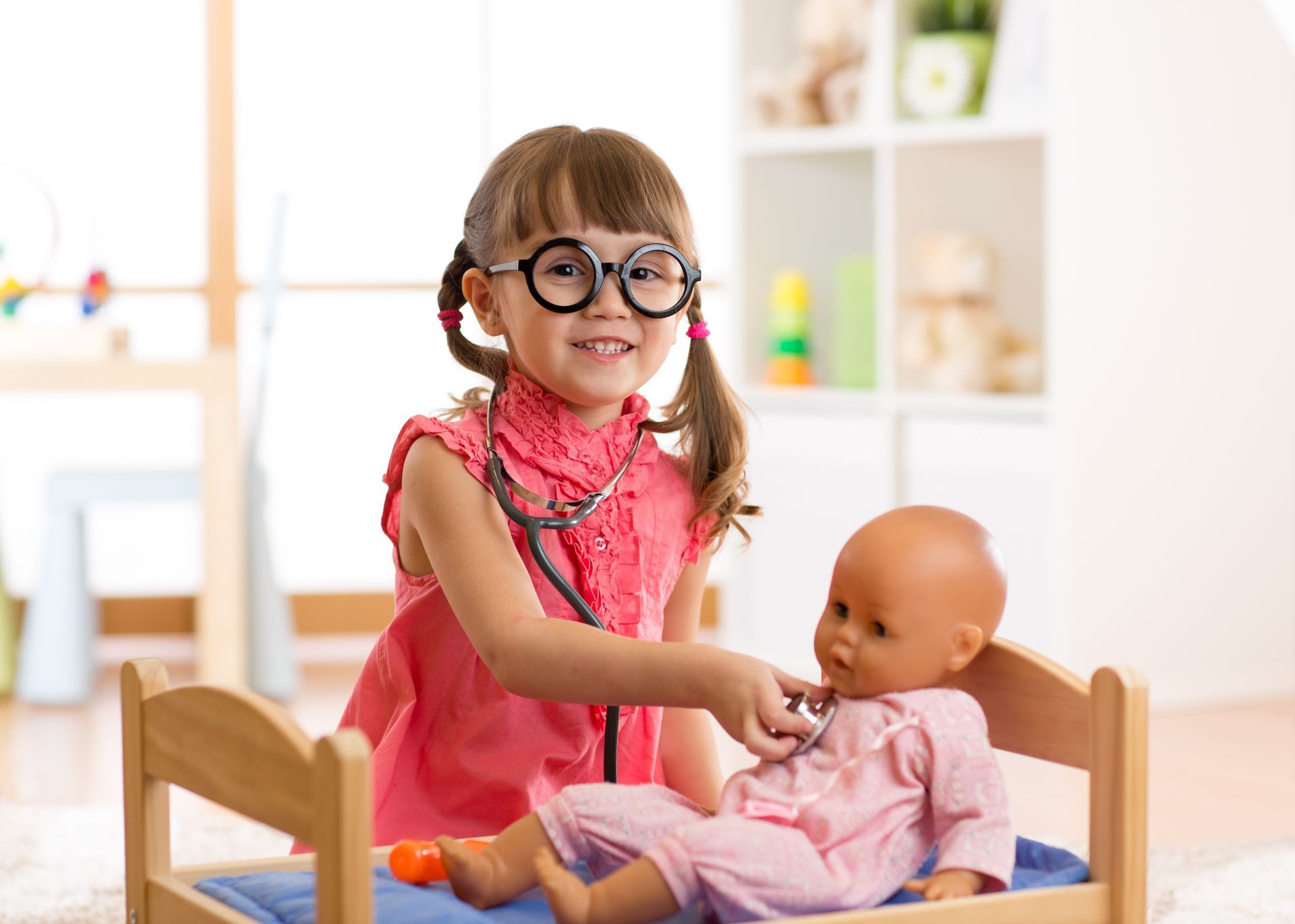 Little girl with stethoscope and toy doll.