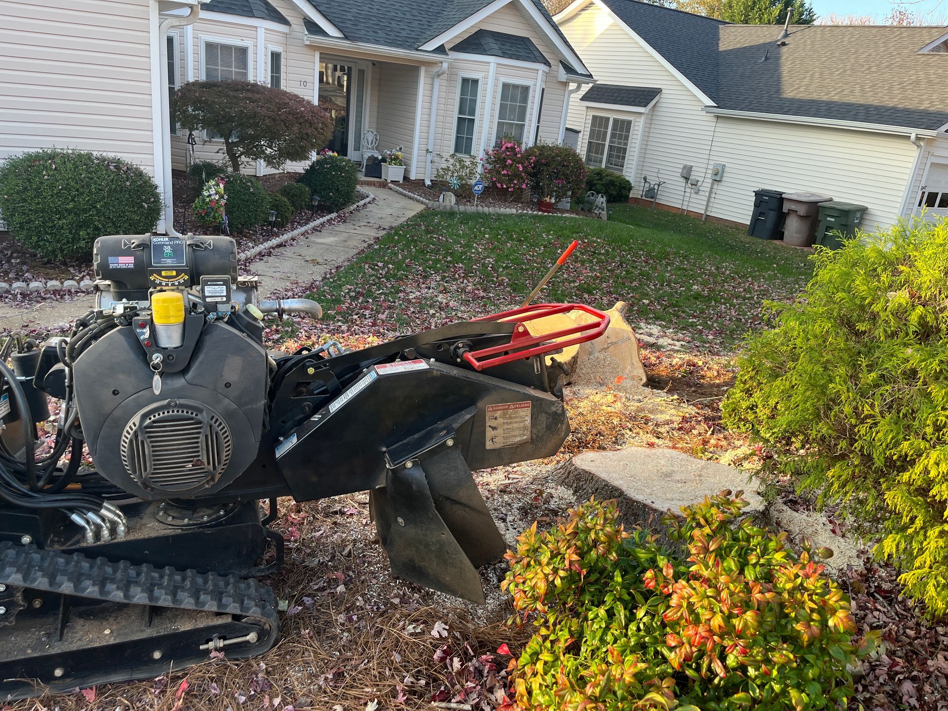 A stump grinder is sitting in front of a house.