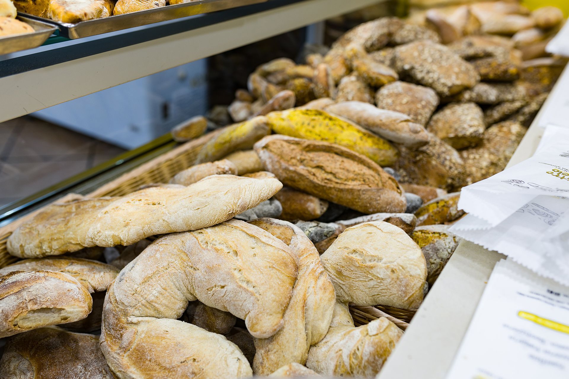 Assortimento di pagnotte di pane e pasticcini esposti su vassoi da forno.