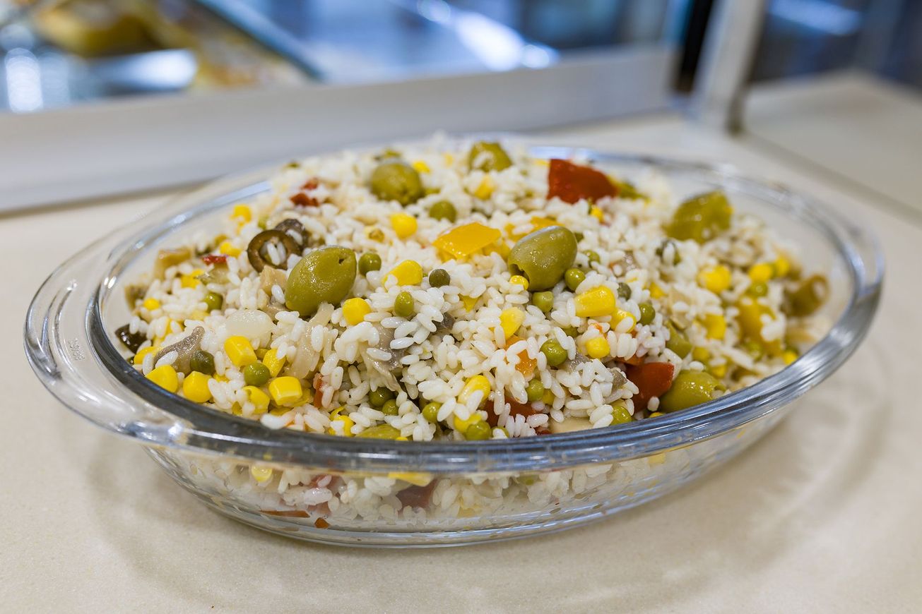 Ciotola di vetro con insalata di riso, mais e olive su un tavolo